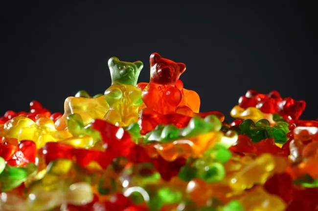 Colorful gummy bears piled together against a dark background